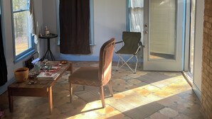 Una habitación iluminada por el sol con un ventilador de techo, una mesa de comedor con sillas y una puerta que da al exterior.