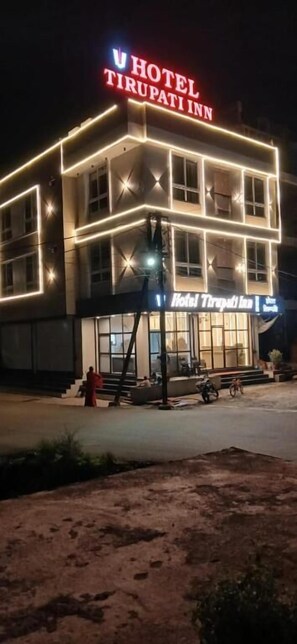 Ett hotell som heter ”Hotel Tirupati Inn”, med en tydlig skylt och upplysta fönster.