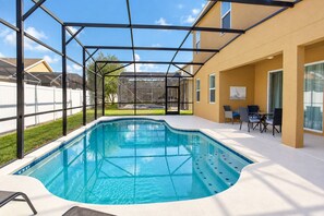 A swimming pool with a glass enclosure, surrounded by a patio area with outdoor furniture. - Spacious Home - Veranda Palms w/ Heated Pool & BBQ (Kissimmee)