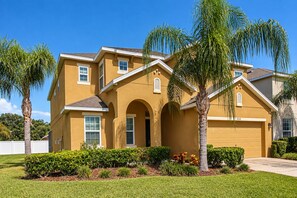 A two-story house with a garage, arched entrance, and a well-maintained lawn. - Spacious Home - Veranda Palms w/ Heated Pool & BBQ (Kissimmee)