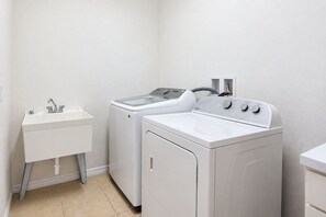 A laundry room with a sink, two washing machines, and a dryer. - Spacious Home - Veranda Palms w/ Heated Pool & BBQ (Kissimmee)