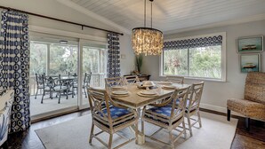 Un espace repas avec une grande table en bois, des chaises en osier et un luminaire suspendu.