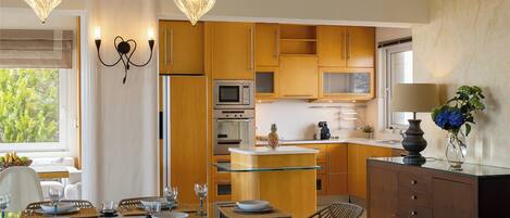 A modern kitchen with wooden cabinets, a glass island, and a dining area with wicker chairs.