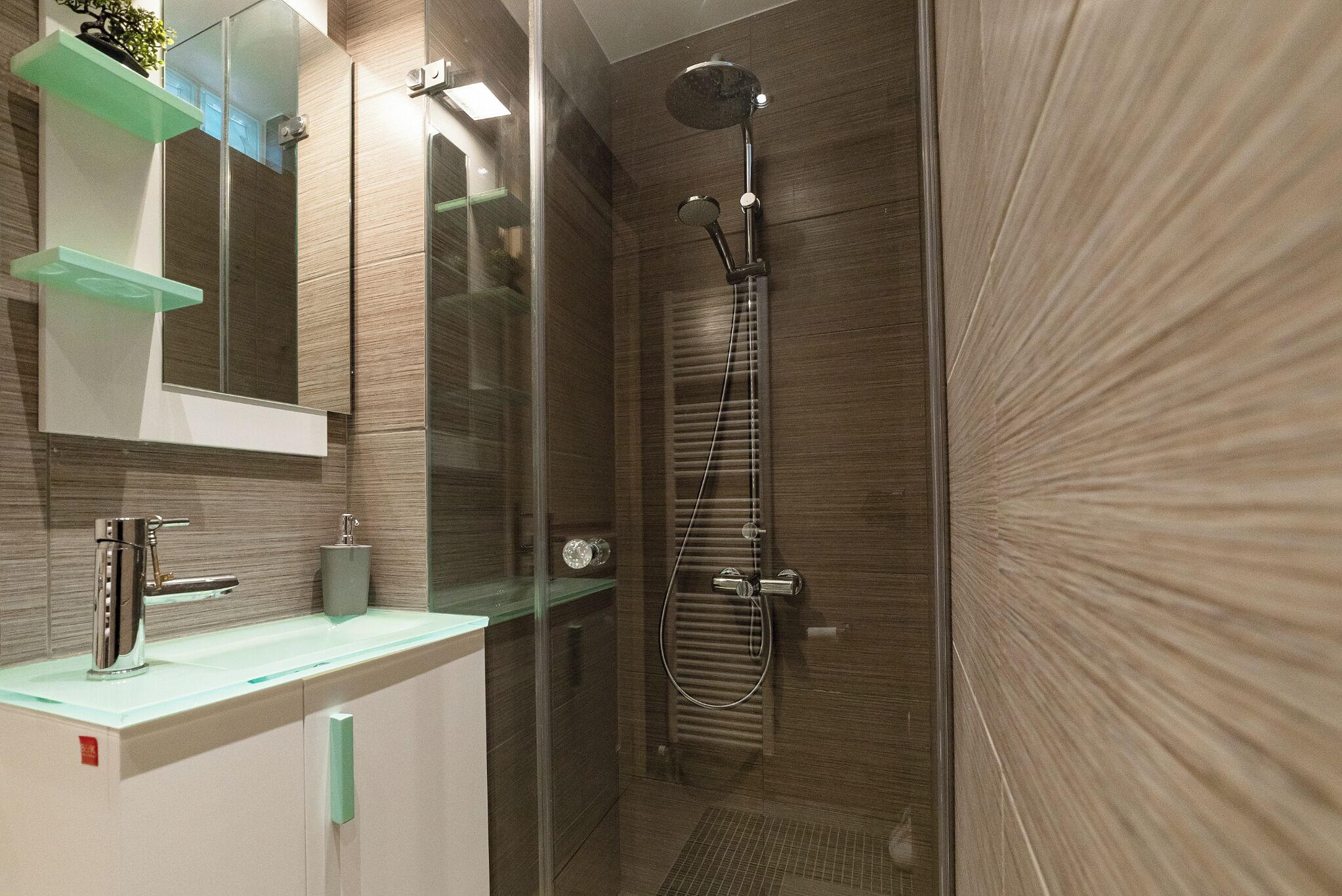 Une salle de bain moderne avec une douche à parois de verre, un meuble-lavabo avec un miroir et un porte-serviettes.