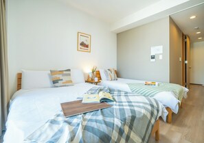 A hotel room with two beds, a nightstand, and a framed picture on the wall. - SR Namba -Sanctuary Residence (Osaka)