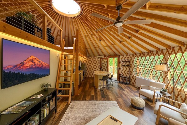 Un intérieur chaleureux, avec des éléments en bois, une grande télévision, un coin cuisine et un espace salon.