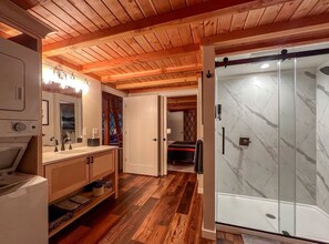 Une salle de bain moderne et compacte, dotée d’une douche, d’un plancher en bois et d’un mur en marbre.
