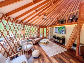 Un intérieur chaleureux et accueillant, avec des murs en bois, un canapé, des fauteuils, une table basse et un téléviseur.