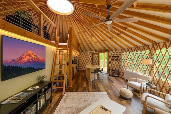 A cozy, wooden interior with a large TV, a kitchen area, and a seating space.