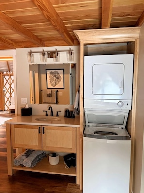 A compact kitchen with a built-in microwave, a sink, and a wooden cabinet.