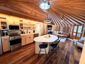 Una cocina moderna con una isla central, piso de madera y un comedor con una mesa redonda y sillas.