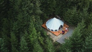 A single-room tent with a circular roof, surrounded by dense forest. - Spacious Bell Tent with Private Deck & Forest Access near Carson, Washington (Carson)
