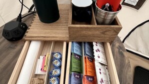 A wooden table with a black power adapter, a black mug, red napkins, and a drawer containing various packaged items. - Spacious Bell Tent with Private Deck & Forest Access near Carson, Washington (Carson)
