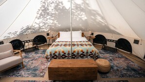 A tent with a bed, two chairs, a wooden bench, and a small round ottoman. - Spacious Bell Tent with Private Deck & Forest Access near Carson, Washington (Carson)