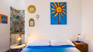 Une chambre à coucher avec un lit, des tables de chevet, un miroir et des œuvres d’art murales.
