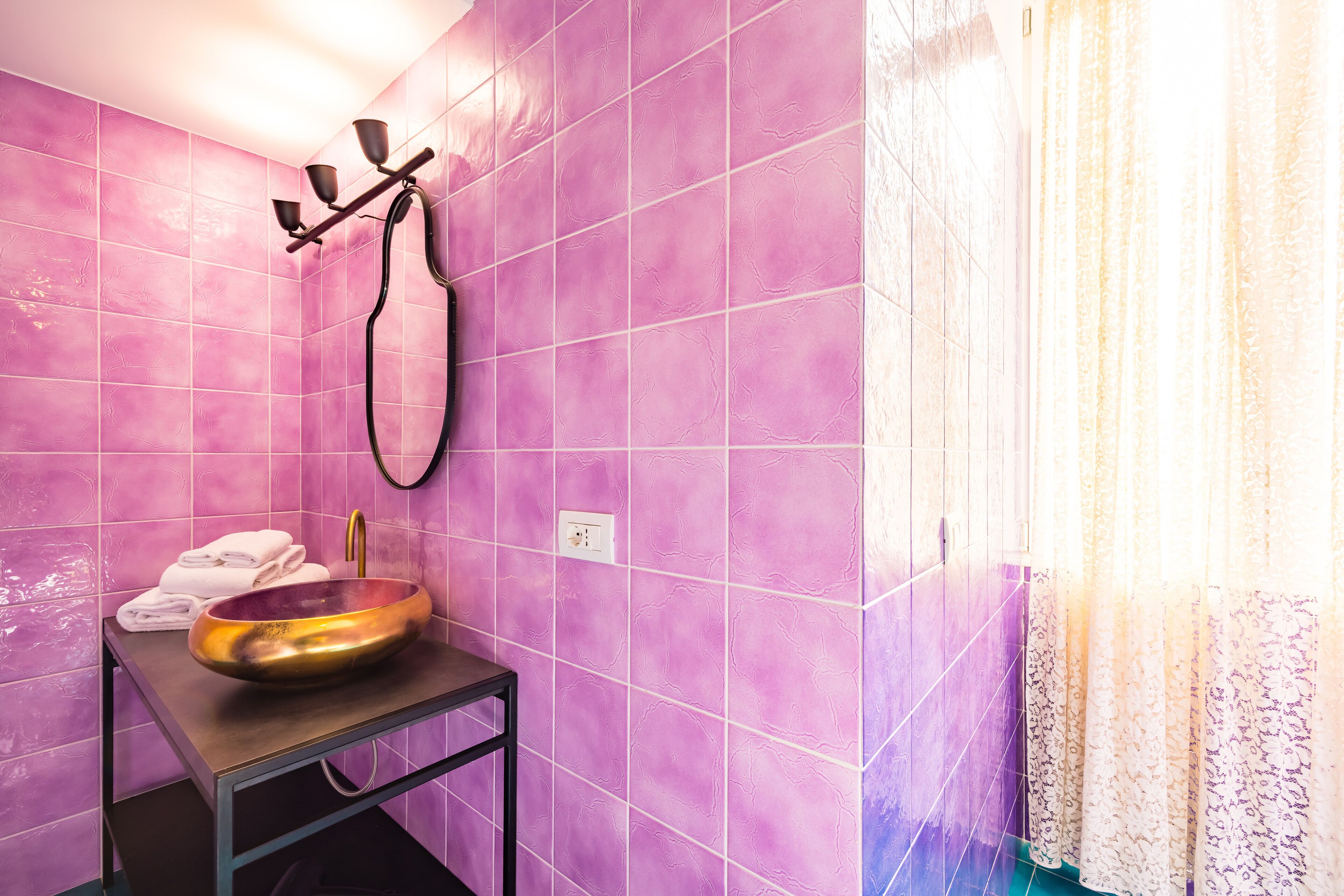 Ein Badezimmer mit violetten Fliesen, einem Waschbecken aus Kupfer und einem Handtuchhalter.