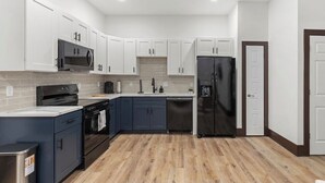 Una cocina moderna con armarios blancos, un refrigerador negro y un microondas.