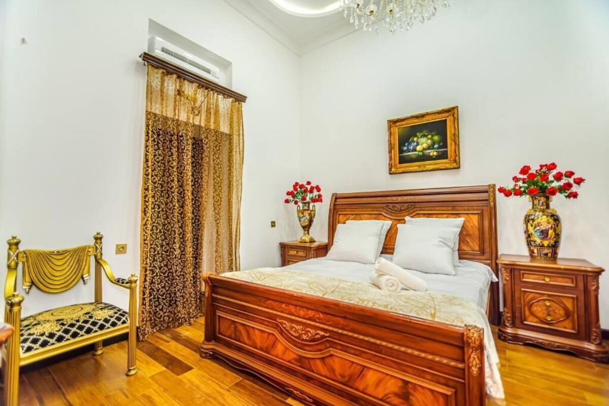 Un dormitorio con una cama de madera, una araña y dos jarrones con flores.