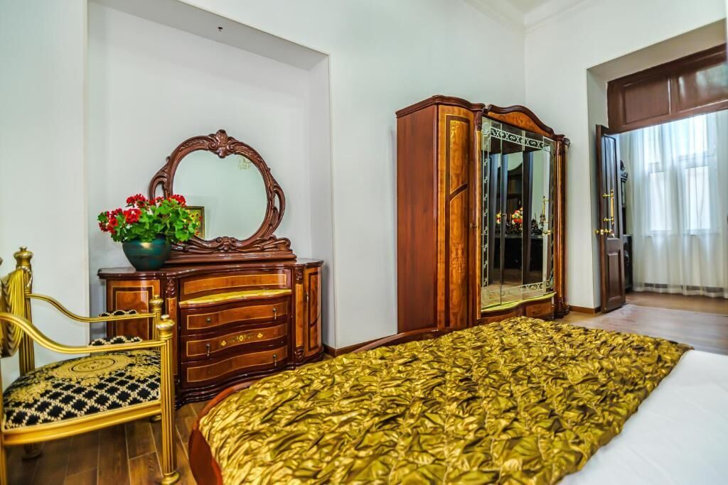 A bedroom with a bed, a wooden dresser, a mirror, and a chair.