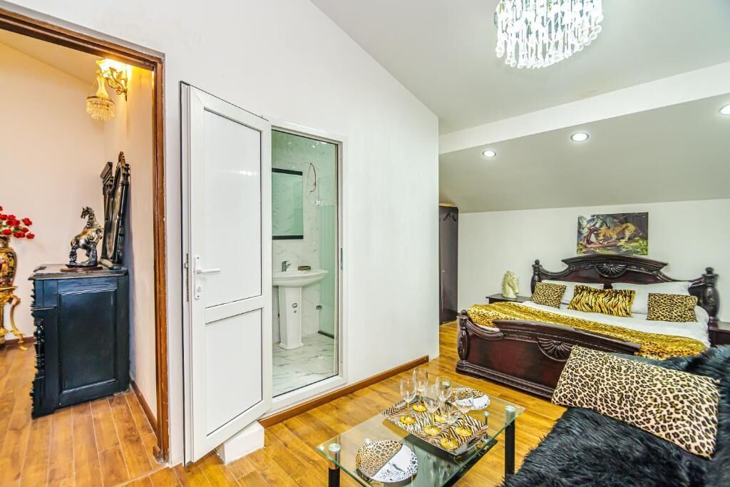 Un amplio salón con una cama grande, una mesa de centro de vidrio y una araña.
