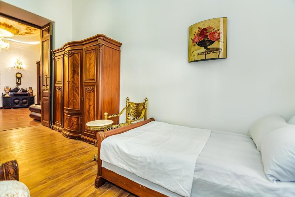Un dormitorio con una cama de madera, un armario de madera, una mesita redonda y un cuadro colgado en la pared.