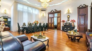 Amplia sala de estar con candelabro, muebles de madera y un comedor con sillas y una mesa.