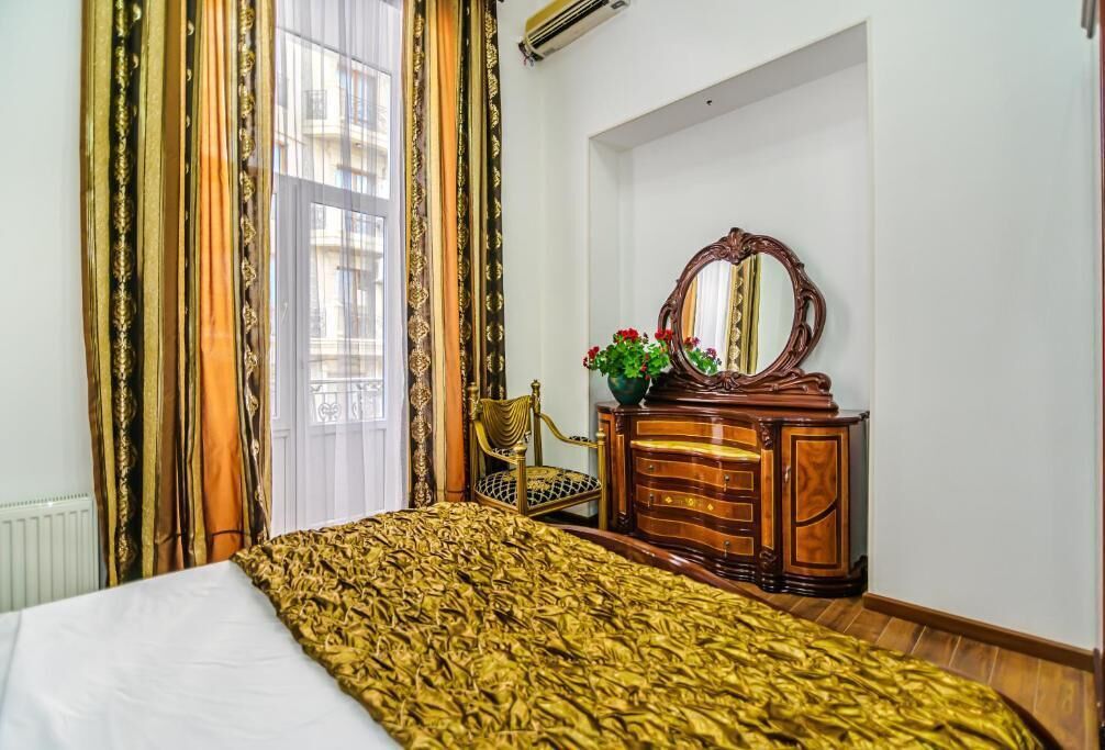 Una habitación de hotel con una cama, un tocador de madera, una silla y un espejo grande.