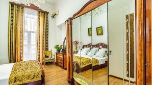 Un dormitorio con una cama grande, un armario de madera, un espejo y una araña.