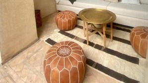 Una habitació amb un sofà blanc, una taula de centre rodona i dos otomans.