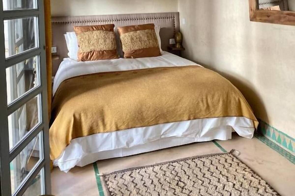 Une chambre à coucher avec un lit, une lampe suspendue, un miroir et un tapis à motifs.