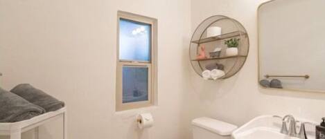 A bathroom with a toilet, sink, and a window with a view.