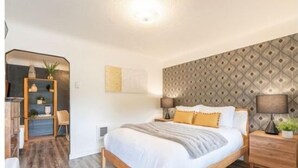 A bedroom with a wooden bed, a nightstand, a mirror, and a wall with a diamond pattern.