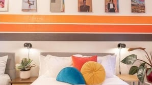 Une chambre d’hôtel avec un lit, des tables de chevet et un mur orné de tableaux.