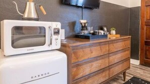 Een kleine keuken met een magnetron, koffiezetapparaat en een houten kast.