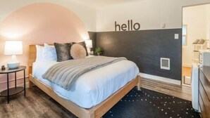 Een moderne slaapkamer met een bed, een nachtkastje, een lamp en een wandplank.