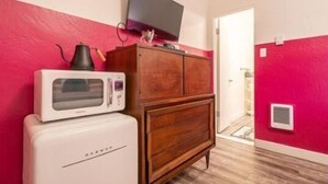 Une pièce de taille modeste, avec un réfrigérateur blanc, un meuble en bois et un téléviseur à écran plat fixé au mur.