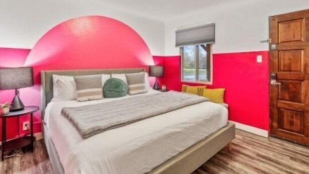 Une chambre à coucher avec un lit, des tables de chevet, une fenêtre et une porte.