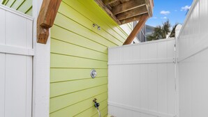 A small, enclosed outdoor area with a green wall, a white fence, and a brick pathway. - Surfside Retreat w/ Pool & Elevator Access (Surfside Beach)