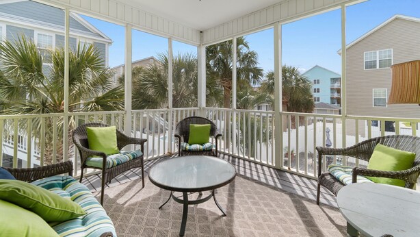 A covered outdoor area with wicker furniture, a glass table, and a ceiling fan. - Surfside Retreat w/ Pool & Elevator Access (Surfside Beach)