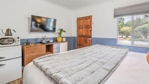 A bedroom with a bed, a television, a wooden door, and a window. - b. under the sea #2 King bedroom (Bandon)