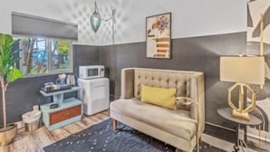 A modern living room with a beige sofa, a white coffee table, a floor lamp, and a painting on the wall. - b.fresh #6 King bedroom (Bandon)