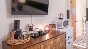 Una cocina moderna con un televisor de pantalla plana montado sobre un mueble de madera. Hay un microondas, un hervidor y una cafetera en la encimera.