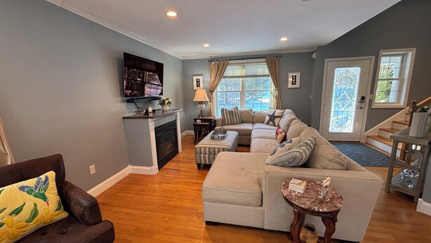 A living room with a fireplace, a sectional sofa, a television, and a dining area. - Half-Acre Coastal Retreat- Hot tub and walk to town! (Ogunquit)