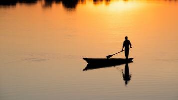 Silueta de una persona remando en un bote sobre aguas tranquilas durante la puesta de sol.
