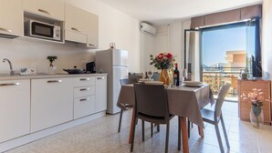 Una cocina moderna con comedor, refrigerador, microondas y una mesa dispuesta para dos.