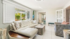Ein geräumiger Wohnbereich mit einem beigefarbenen Sofa, einem grauen Sessel und einem Couchtisch.