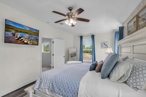 A bedroom with a bed, a ceiling fan, a window with curtains, and a painting on the wall. - 5 BR Houston Retreat - Private Loft + Huge Deck - Sleeps 12 (Houston)
