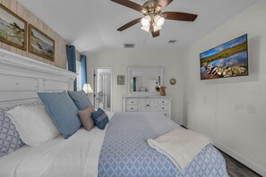 A bedroom with a bed, a ceiling fan, a dresser, a mirror, and a painting on the wall. - 5 BR Houston Retreat - Private Loft + Huge Deck - Sleeps 12 (Houston)