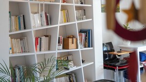 Una habitación con una estantería blanca llena de libros y una lámpara colgante decorativa.