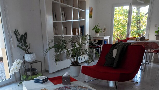 Una sala de estar moderna con un sillón rojo, una mesa de centro blanca y una estantería.